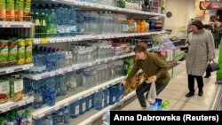 O locuitoare a Kievului cumpără apă într-un supermarket, după ce aproximativ 80 la sută dintre locuitorii capitalei ucrainene au rămas fără apă, potrivit primarului, în urma unui atac cu rachete rusești.