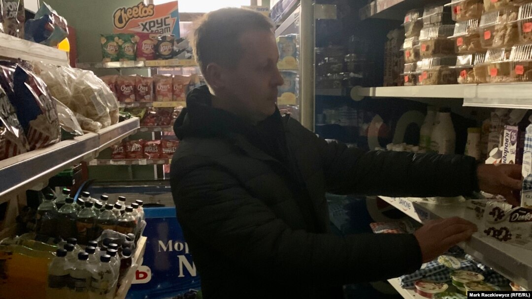 Yuriy Filimonov stocks a dairy shelf amid a rolling blackout on November 6 in Kyiv.
