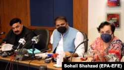 Information Minister Fawad Chaudhry (center) and Human Rights Minister Shireen Mazari (right) talk with journalists during a press conference in Islamabad in April 2021.