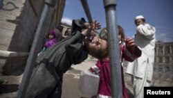 A Kuchi boy tries to drink water in front of the ruins of Darul Aman palace in Kabul.