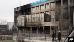 Прохожие рядом с офисным зданием компании «Озенмунайгаз», горевшим во время Жанаозенских событий. 17 декабря 2011 года.