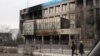 Kazakhstan - Residents walk past a burnt UzenMunaiGas office in Zhanaozen, Kazakhstan, Saturday, Dec. 17, 2011. Violent clashes broke out Friday between police and demonstrators in an oil town in western Kazakhstan. Authorities in Kazakhstan said Saturday