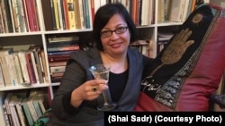 Shadi Sadr sits on the "Islamic" couch with a wine glass.