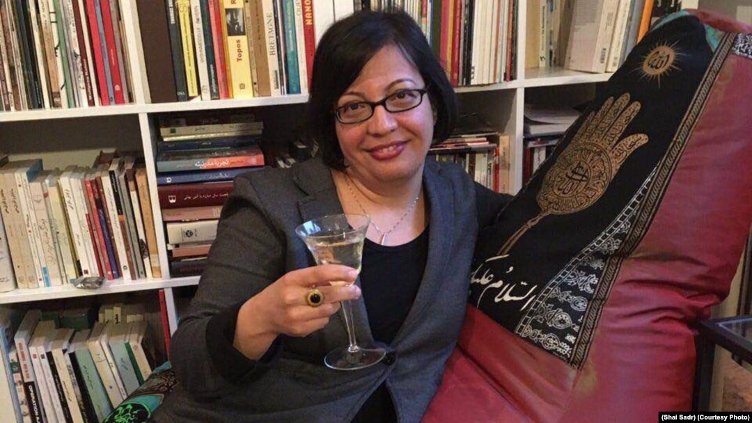 Shadi Sadr sits on the "Islamic" couch with a wine glass.