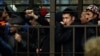 Migrant workers line up in a fenced holding area outside a Federal Migration Service office in Moscow as they wait for their turn to get a work permit.