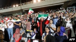 IRAN -- Iranian soccer supporters wave their national flags as they cheer for their national team during a screening of the Russia 2018 World Cup Group B football match between Iran and Spain in Azadi stadium in the capital Tehran, June 20, 2018