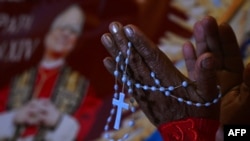 O femeie rugându-se la catedrala din Chiclayo, în Peru, în fața unui afiș cu Robert Prevost, care tocmai fusese ales papă pe 8, mai 2025