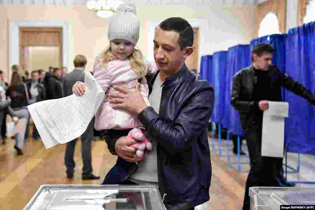 A little girl casts a man&#39;s ballot in Kyiv. (AFP/Sergei Supinsky)