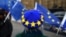 EU flag -themed beret while waving EU flags