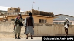 Taliban fighters stand guard in the city of Ghazni on August 13.