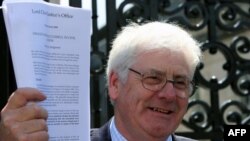 Michael Gallagher, who lost his son in the Omagh bombing, holds the successful civil action judgement outside the High Court in Belfast, Northern Ireland.