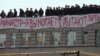 Inmates stand on a roof of Prison No. 6 in Kopeysk with a sign that says, &quot;The [prison] administration extorts money and tortures us.&quot;