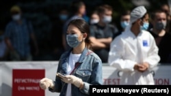 Женщина в защитной маске и перчатках у пункта тестирования на коронавирус. Алматы, 17 июня 2020 года.