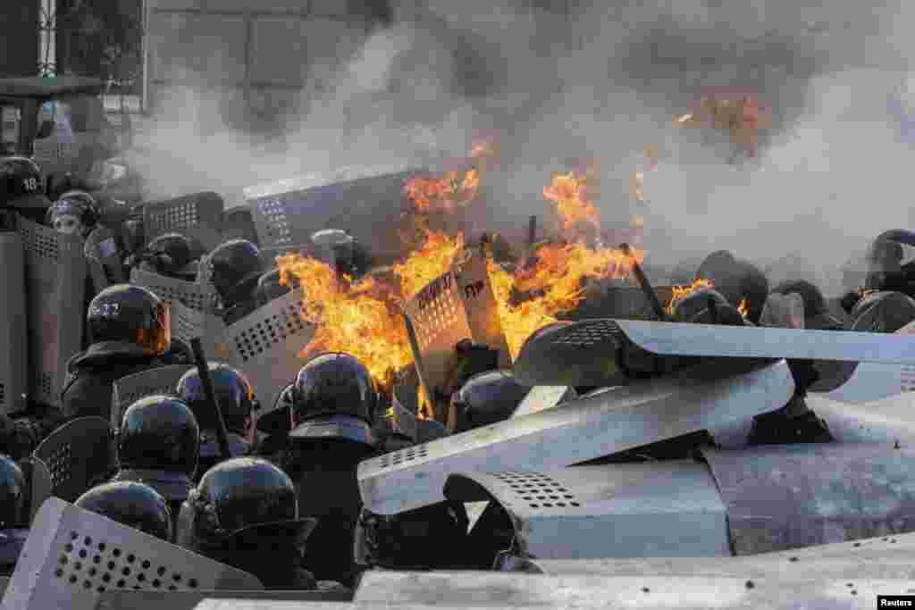 Flames rise from a group of riot police during clashes with protesters.