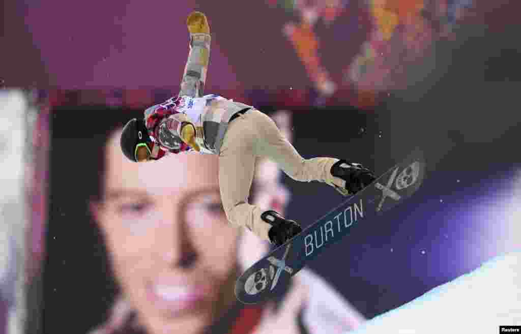 U.S. star snowboarder Shaun White jumps near a picture of himself during the men's snowboard halfpipe qualification round.