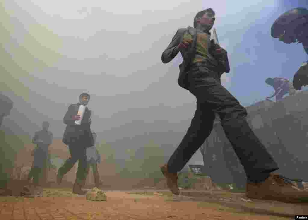 A riot policeman gestures to people to run from an area filled with smoke on Taghyeer (Change) Square after demolished huts were set on fire, in Sanaa, Yemen. Authorities deployed riot police and used bulldozers to demolish the huts set up by pro-democracy protesters. (Reuters/Khaled Abdullah)