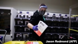 Election worker Gareth Fairchok removes ballots from a sorting machine as vote-by-mail ballots for the August 4 Washington state primary are processed at King County Elections in Renton, Washington on August 3, 2020.