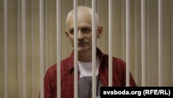 Belarusian human rights activist Ales Byalyatski stands in a guarded cage during his trial for tax evasion in Minsk.