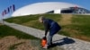 An employee sprays grass seed in front of the Bolshoi Ice Dome at the Olympic Park in Sochi on February 4.