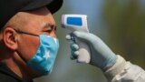 Kyrgyzstan - Bishkek - Generic - COVID-19 - coronavirus - A security officer in a protective mask checks the temperature of a passenger following the outbreak of a new coronavirus, at an away in Bishkek, a region bordering Sokuluk.