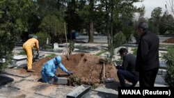 Men bury journalist Abdollah Zavieh, who passed away due to coronavirus disease (COVID-19), at Behesht Zahra cemetery in Tehran, March 24, 2020