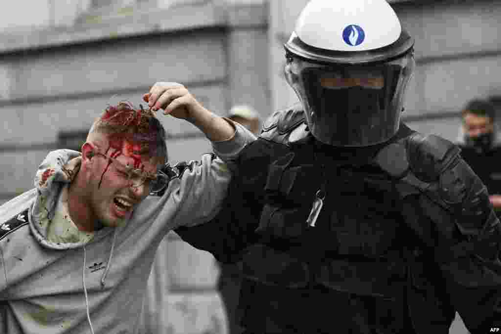 Un ofițer de poliție ține un protestatar rănit.