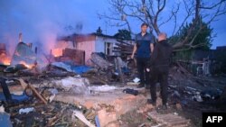 Місцеві жителі оглядають залишки свого зруйнованого будинку після атаки російського безпілотника в передмісті Харкова, 21 травня 2024 року