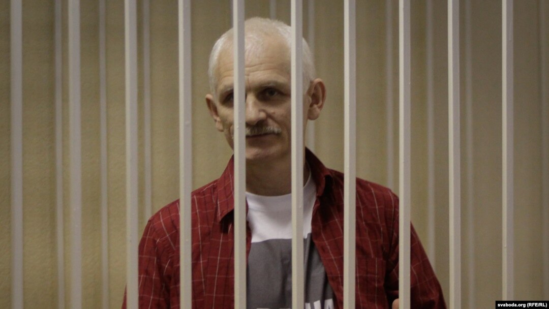 Belarusian human rights activist Ales Byalyatski stands in a guarded cage during his trial for tax evasion in Minsk.