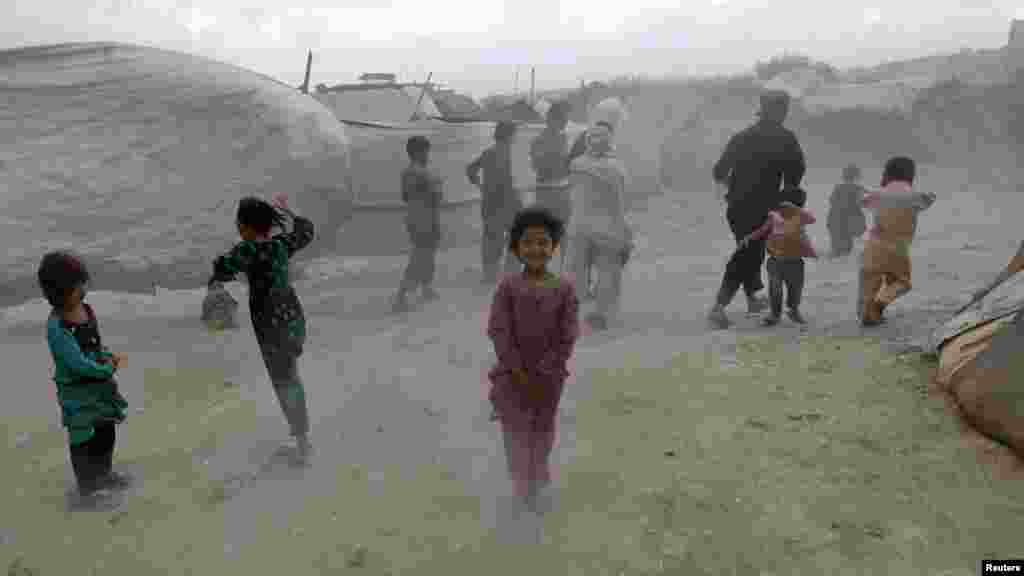 Internally displaced children shield themselves from dust picked up by wind at a refugee camp in Kabul. (Reuters/Omar Sobhani)