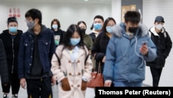 People wearing protective masks in a subway tunnel during evening rush hour in Beijing on March 10.