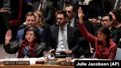 U.S. -- Karen Pierce (L), British Ambassador to the United Nations, and Nikki Haley, United States Ambassador to the United Nations, vote in favor of a resolution for an independent investigation on the use of chemical weapons in Syria, New York, April 10