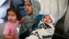 A Syrian refugee woman holds her 40-day-old son as a girl stands with them at a makeshift camp for refugees and migrants at the Greek-Macedonian border near the village of Idomeni, Greece. Syrian refugees are banned from entering the United States indefinitely under an executive order signed by U.S. President Donald Trump. (file photo)