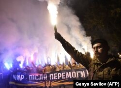 Demonstrators chant slogans and raise flares during a rally in Kiev on October 14, 2016.