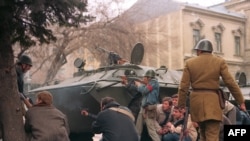 A group of anticommunist civilian fighters and a Romanian soldier take cover from sniper fire, supposedly from pro-Ceausescu forces.