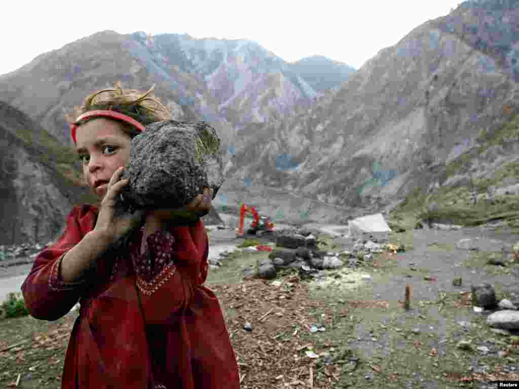 A Kashmiri girl refugee carries a stone to helps her father to build a wall in the Neelum Valley near Kamsar camp, some 10 km (6 miles) north of the earthquake-devastated city of Muzaffarabad in Pakistan-administered Kashmir February 15, 2006. Winter weather has made life more difficult for survivors of last year's massive earthquake in South Asia, where more than two million people have been living in tents or crude shelters patched together from ruined homes. REUTERS/Thierry Roge 