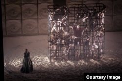 O mare sculptură umană din actori și figuranți urcați pe o structură metalică alături de Sfinx, care îl provoacă pe Oedip.