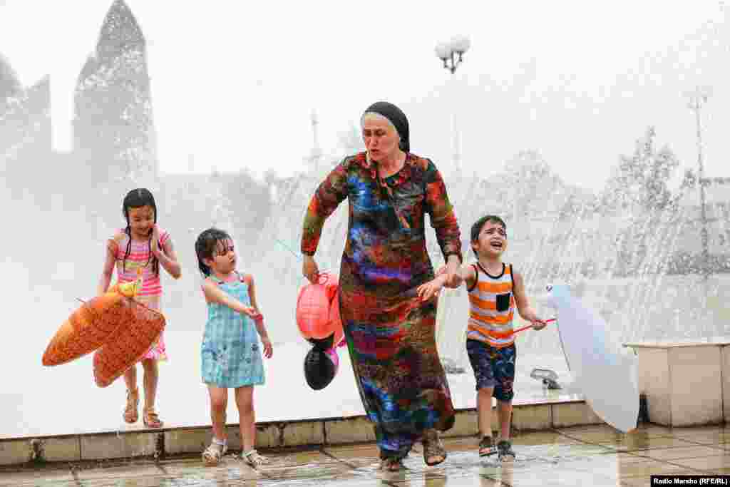 Three kids reluctantly head home after cooling off in a fountain.