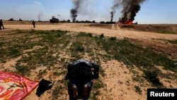 An Iraqi militia fighter kneels as he celebrates victory while smoke rises from a clash with Islamic State militants, in the town of Al-Alam on March 10.