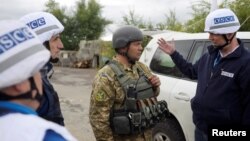 Monitors from the Organization for Security and Cooperation in Europe (OSCE) speak with a Ukrainian serviceman as they visit the town of Zolote in the Luhansk region on September 26. 