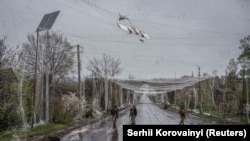 Військовослужбовці йдуть вулицею під антидроновою сіткою у прифронтовому місті Дружківка,  24 квітня 2026 року