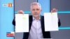 Стоп кадър от предаването "Още от деня" на БНТ от 33 юни 2021 г. Николай Хаджигенов показва документи, които, според него, доказват подслушването на политици.