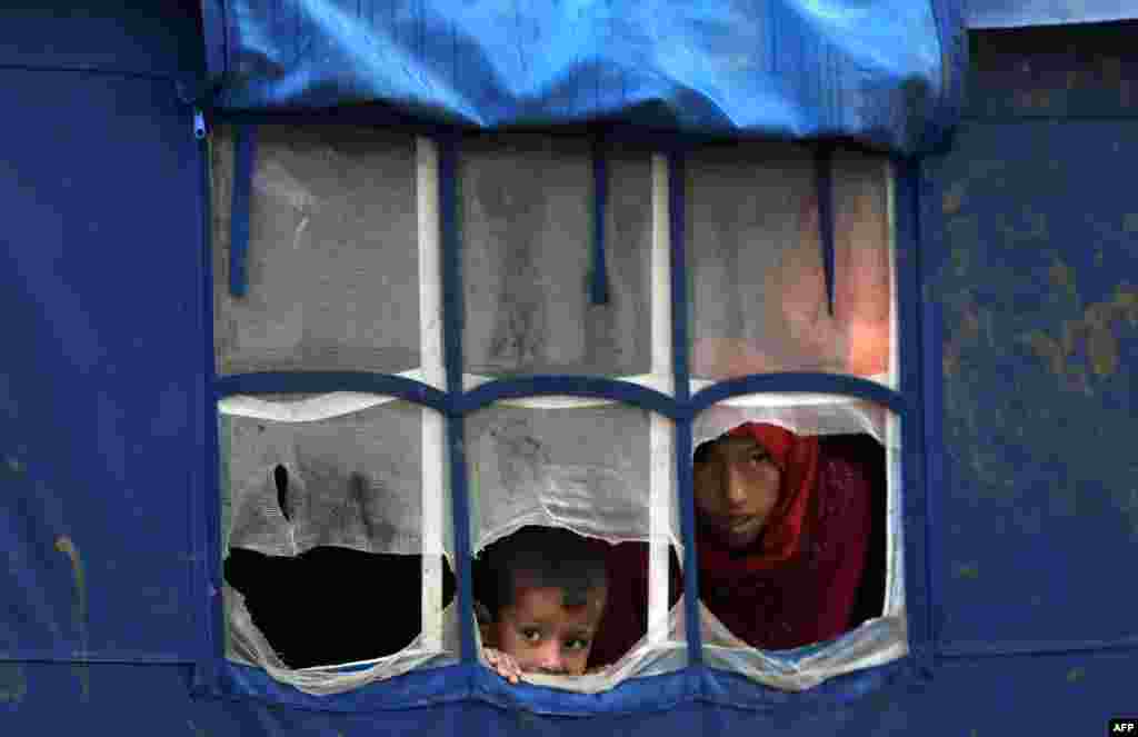 Displaced Iraqi children look out from a tent at a camp in Baghdad following heavy rains. (AFP/Ahmad al-Rubaye)