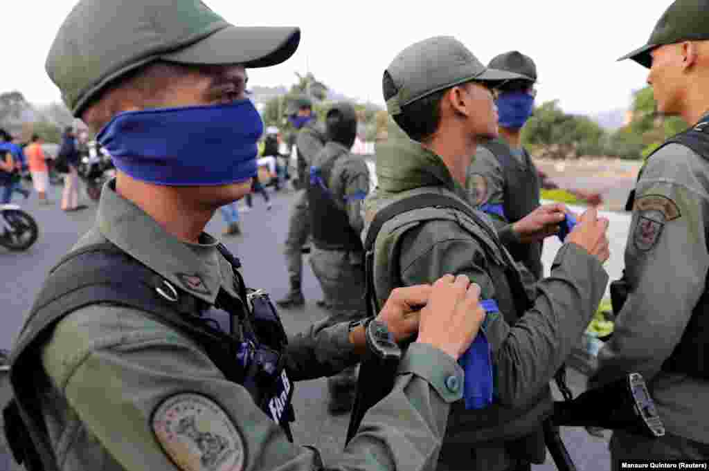 Armed men apparently aligned with Guaido don blue armbands.&nbsp;