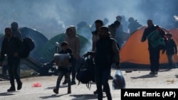 Migrants in Bosnia carry their belongings near a border crossing with Croatia. (file photo)