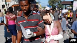 An injured woman is helped after being rescued in Port-au-Prince.