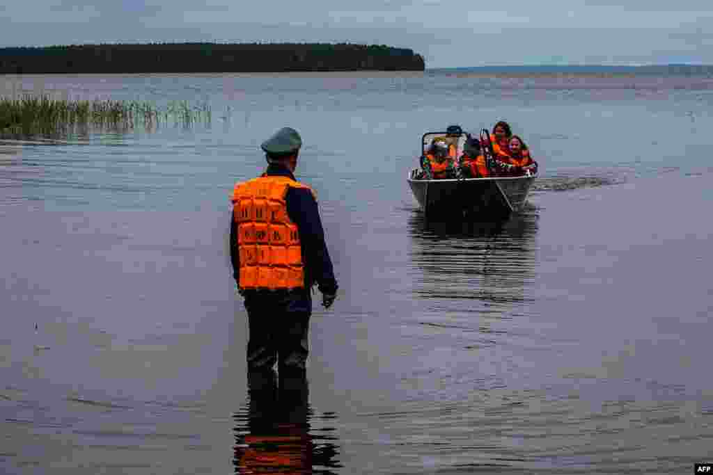 Emergency workers carry surviving children in a boat on Lake Syamozero in Russia's Karelia region on June 19. At least 14 died when two boats capsized on the lake at the weekend. (AFP)