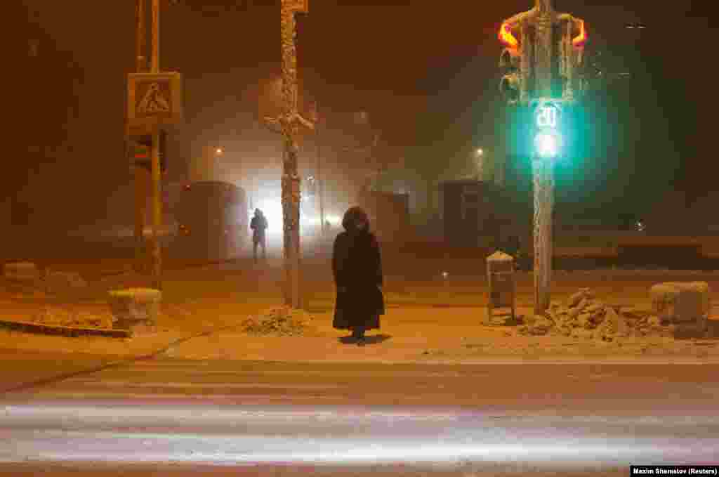 A woman waits near traffic lights and signs covered with hoarfrost as the air temperature sank to minus 46 degrees Celsius (minus 50.8 degrees Fahrenheit) in the eastern Siberian city of Yakutsk on January 16.