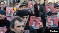 Protesters hold pictures of journalist Tetyana Chornovol, who was beaten hours after publishing an article on the assets of top government officials, during a December 25 rally in front of the Ukrainian Ministry of Internal Affairs in Kyiv.