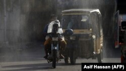 Workers spray disinfectant along a street as a preventive measure against the spread of the coronavirus in Karachi.