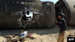 Pakistan -- A policeman photographes the wrackage of a train after a bomb destroyed it in Naseerabad district, Balochistan province, October 21, 2013